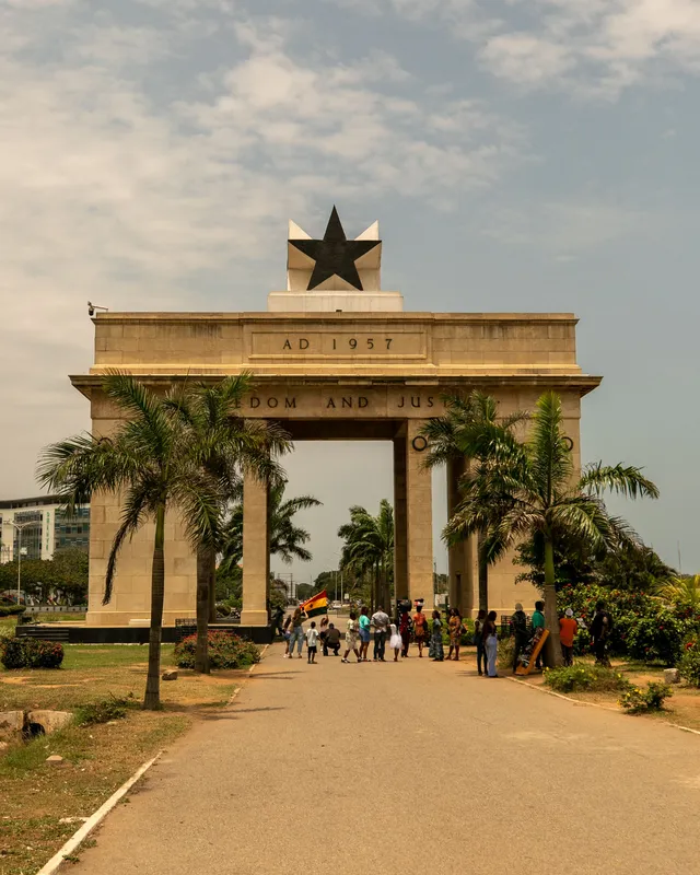The iconic Independence Arch in Accra, Ghana with people walking on a sunny day.