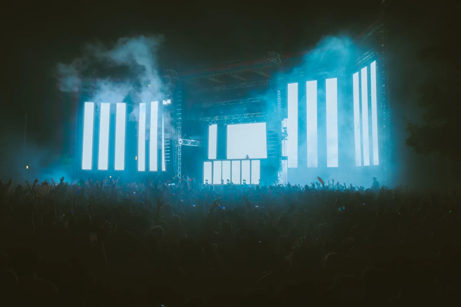 Energetic crowd at a night music festival featuring large LED screens and colorful lighting effects.