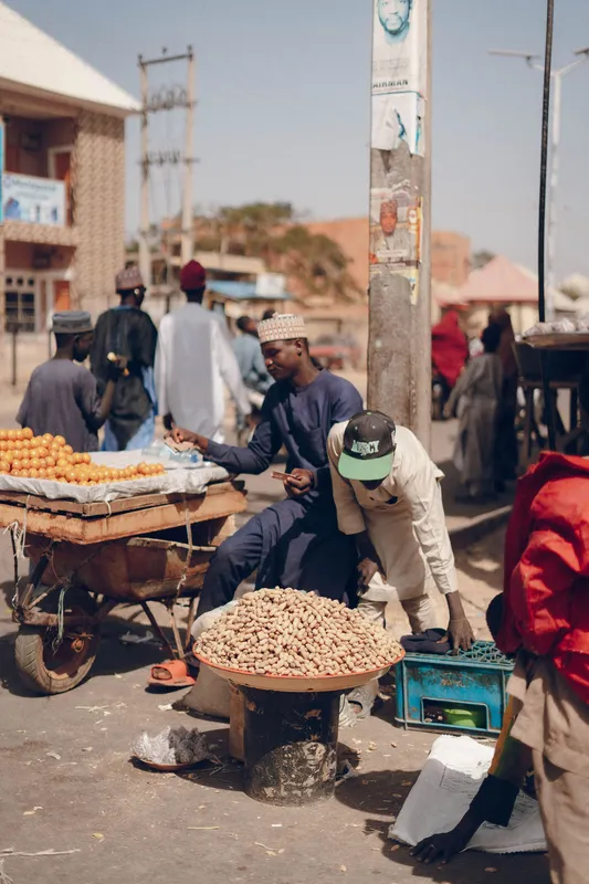 Lively street market in Africa with vendors selling fruits and peanuts.