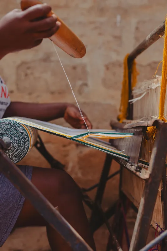 Close-up of hands weaving Kente fabric, showcasing traditional craftsmanship.