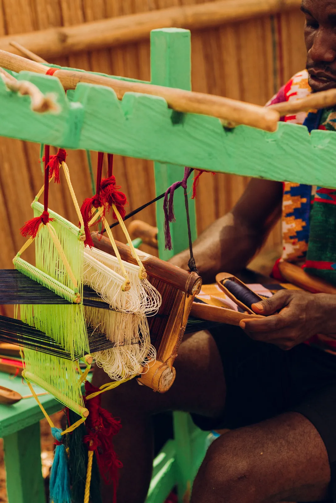A craftsman weaves colorful Kente cloth on a traditional loom in Accra, Ghana.